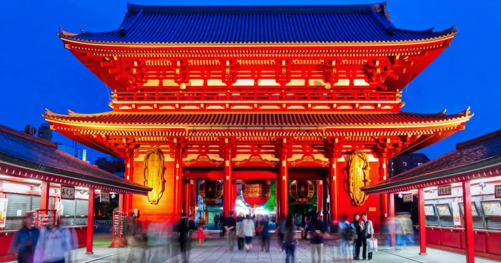Night view of Senso-ji Temple in Asakusa, Tokyo, illuminated in red with visitors walking through the historic gate. A popular attraction for first-time travelers exploring Japan’s cultural landmarks.